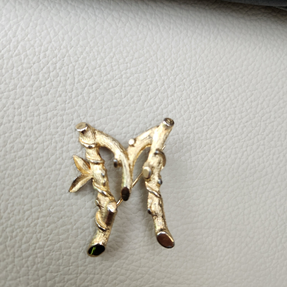 Sarah Coventry "Sarah's ABC's" initial "M" brooch in a gold-tone bamboo design.